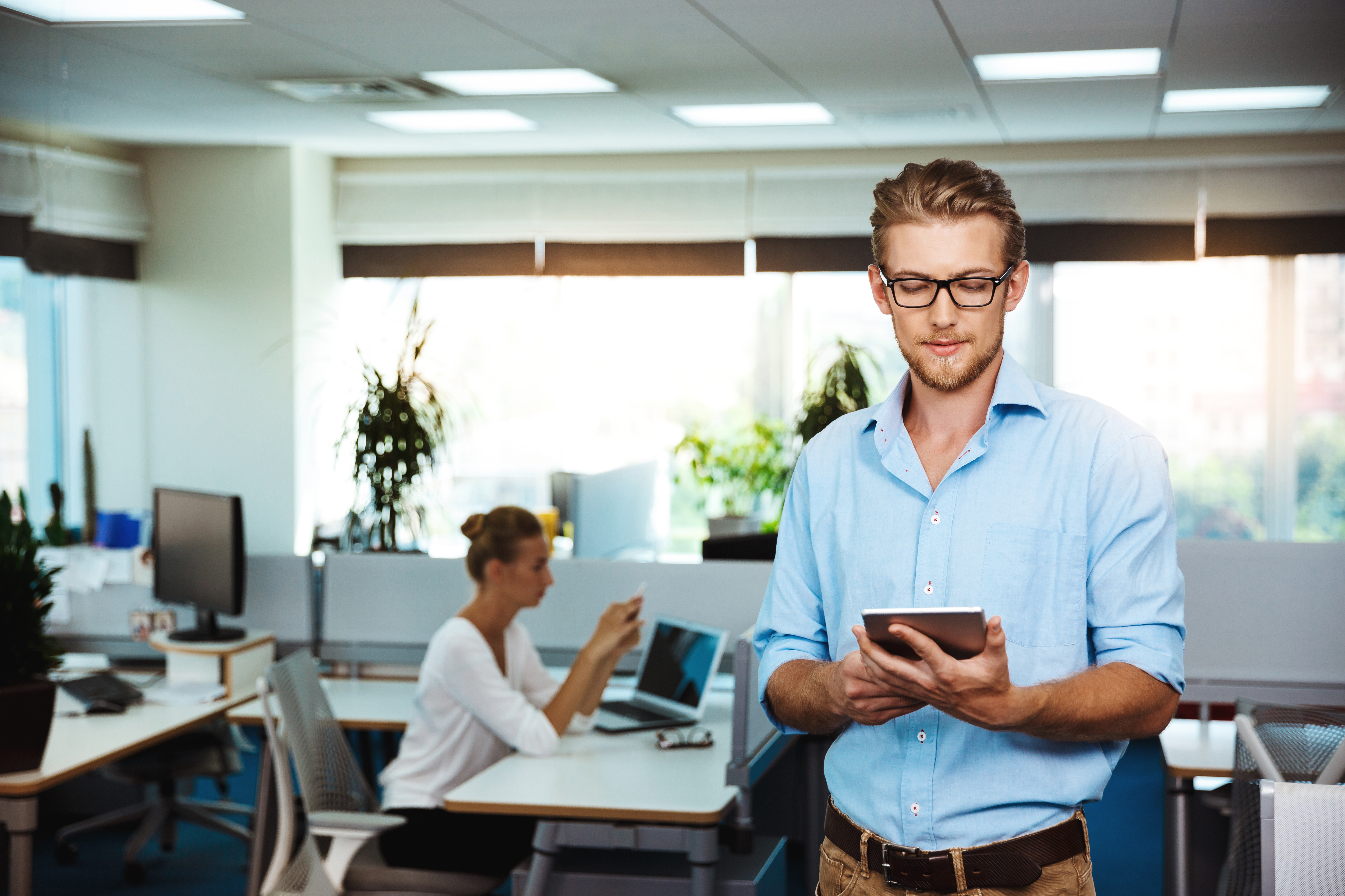 young-successful-businessman-smiling-looking-tablet-office